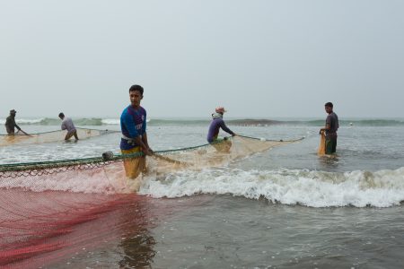 Village men fishing on the Bay of Bengal in low tide waves Men hauling nets at Cox's Bazar Fishing Village