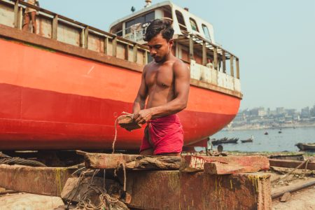 The workers are fit and toned without any gym equipment Repairing wooden parts in heat at Dhaka, Bangladesh Shipyard.