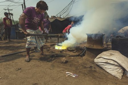 Extreme heat near workers without protective gear. Heating tools are used to manipulate metal parts at Dhaka, Bangladesh Shipyard.