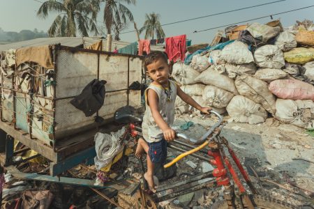 The little boy pretends to drive the rubbish collection cart. Little boy pretends to drive the rubbish collection cart in Chittagong, Bangladesh.