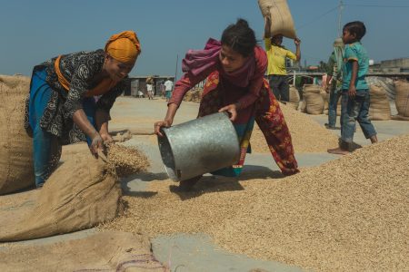 Mother and daughter work together to package milled rice into a sack Women filling hessian bags with rice at Dhaka, Bangladesh Dhaka, Bangladesh Rice Mills.